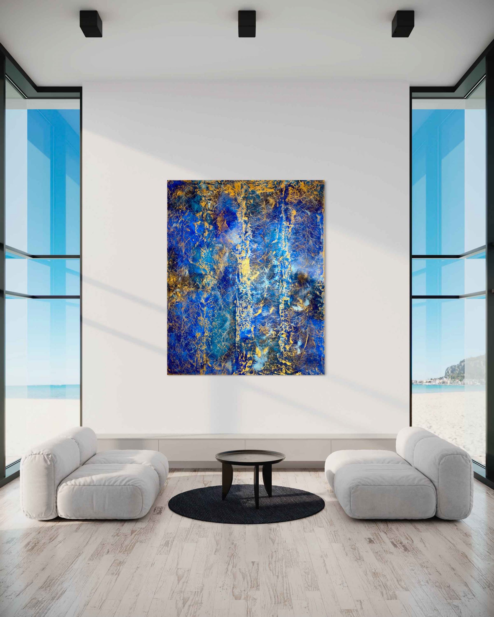 bstraktes, blau-goldenes Gemälde in einem modernen, lichtdurchfluteten Raum mit zwei weißen Sofas, einem schwarzen Teppich und einem runden Couchtisch. Große Glasfenster geben den Blick auf eine Strandlandschaft frei.